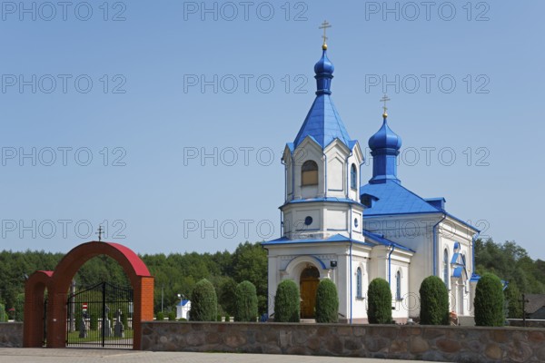 Orthodox church with blue roof and magnificent archway, surrounded by green landscape, Orthodox