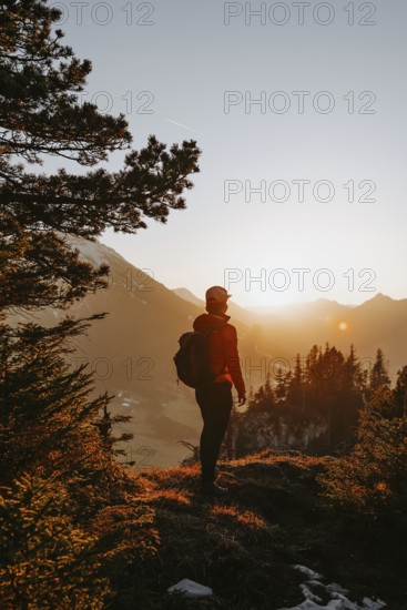 Hiker in the Allgäu at sunset in spring on the Zirmgrat near Pronten in the Allgäu