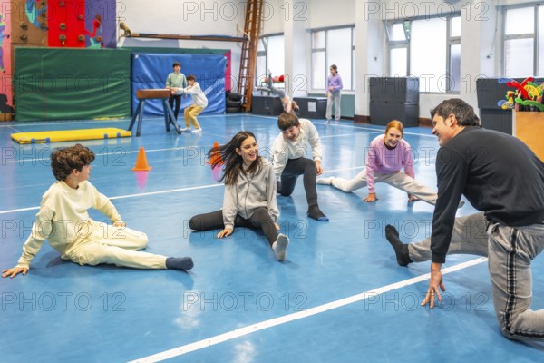 Group of smiling students practicing stretching exercises with their teacher during physical