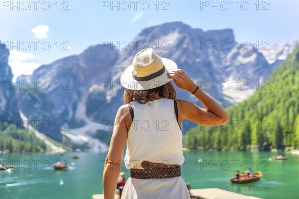 Woman wearing summer hat enjoying stunning landscape of lake braies, also known as pragser wildsee,