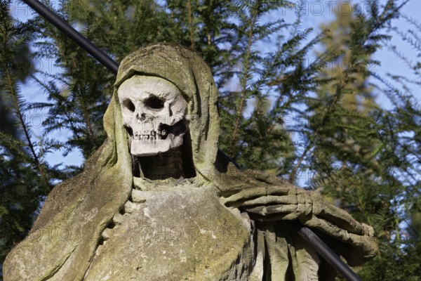 Grim Reaper, allegory of death with hourglass and scythe, sculpture at the Melaten Cemetery,