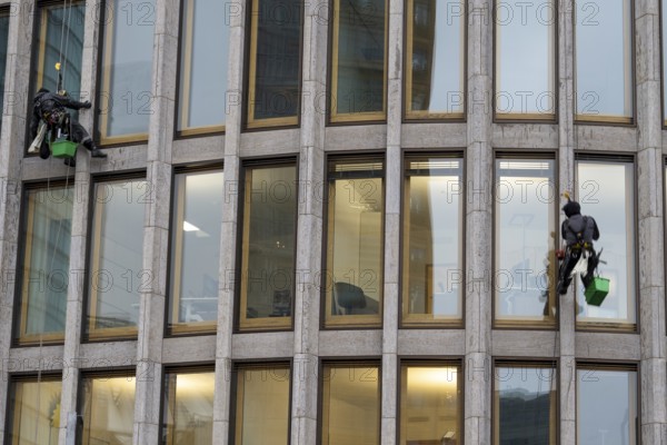 Window cleaners hanging on the facade of a commercial building, Potsdamer Platz, Berlin, Germany