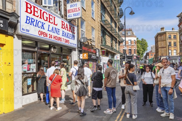 Customers queuing outside a bagel shop, Brick Lane Market, East End, London, England, United