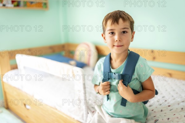 Portrait of a schoolboy with school bag ready for first day at school smiling at camera in the