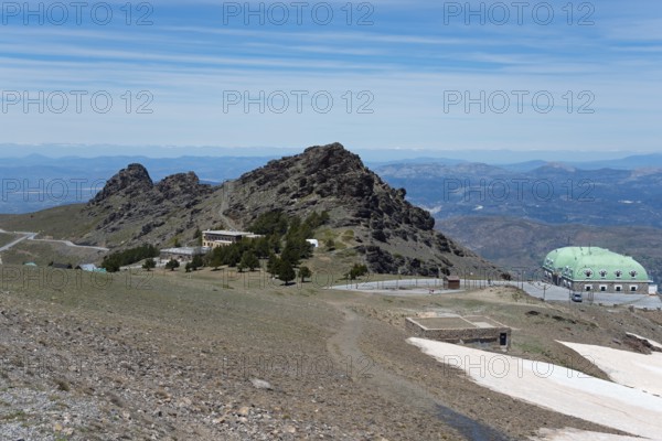 Barren mountains with green dome-like buildings and a wide view over the mountain landscape, on the