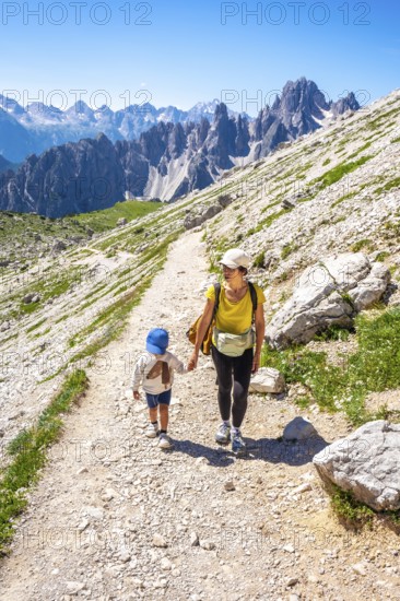 Tourists enjoying a summer hike on a mountain path in the italian alps, with breathtaking views of