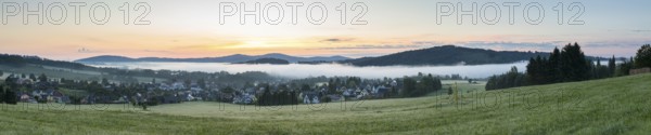 Panorama of the village view with the church of St. Mary's Assumption in the morning fog in front