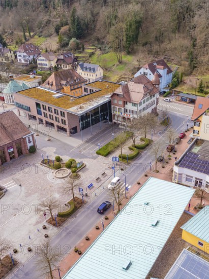 Buildings and streets of a small town surrounded by trees, pastel-coloured architecture and rural
