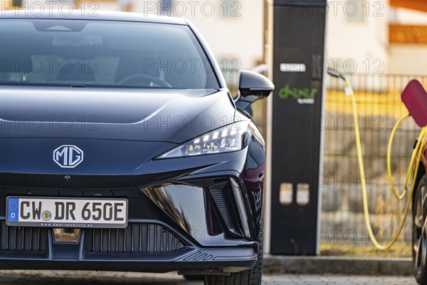 Front of a black electric car with licence plate next to a charging station, Deer E- Carsharing