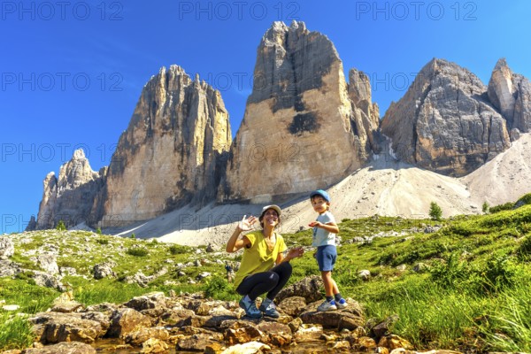Mother and child waving near tre cime di lavaredo, dolomites, italy, enjoying summer vacation