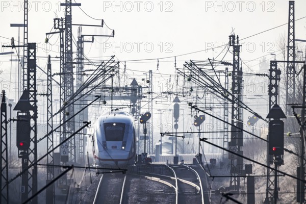 Deutsche Bahn AG tracks with ICE train against the light. Overhead line, signals and infrastructure