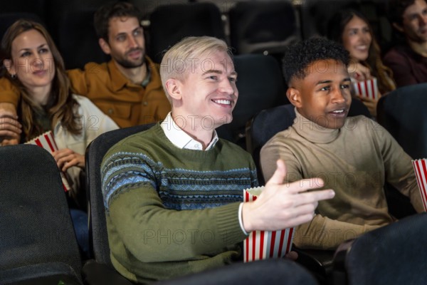 Group of diverse friends watching a film at the movie theater, commenting the scene and smiling,