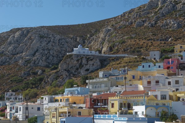 Colourful houses of Menetes with the chapel of Agios Spiridonas on a rock in front of a hill,