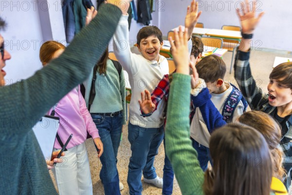 Group of cheerful elementary school students and teacher raising hands together in classroom,