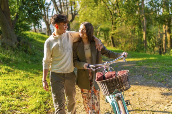 Young couple walking hand in hand through a picturesque park, riding a bicycle and basking in the