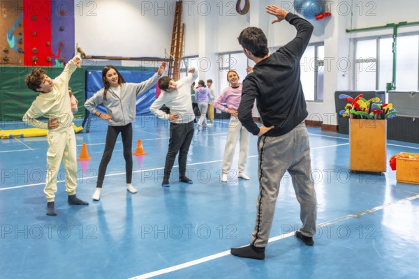 Students and teacher practicing stretching exercises during physical education class in a school