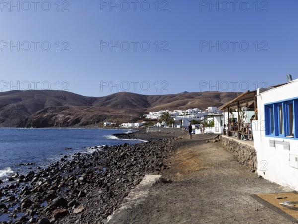 Black lava beach, white houses, fish restaurant, coastline, fishing village Playa Quemada, Yaiza,