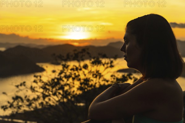 Silhouette of a tourist enjoying a beautiful golden sunset over coron island from mount tapyas