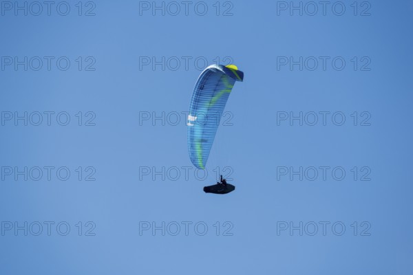 A paraglider soars through a clear blue sky that promises adventure and freedom, Schwangau near