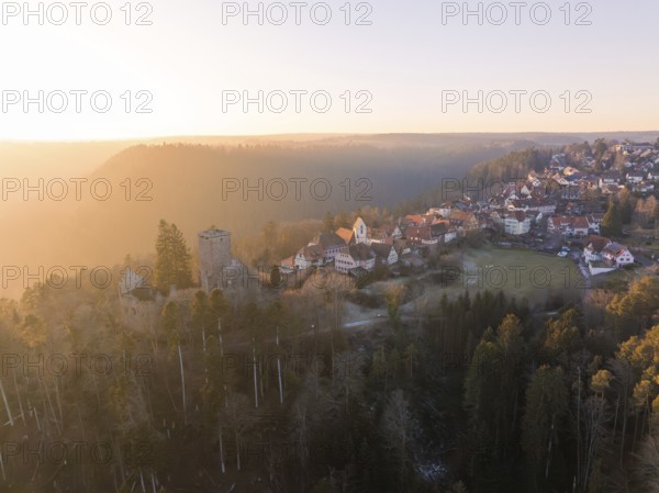 View of a village with a ruin in a hilly forest landscape at sunset, Zavelstein, district of Calw,