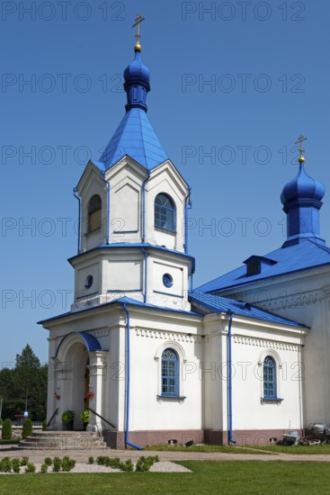White orthodox church with a striking blue roof, surrounded by nature under a bright sky, Orthodox