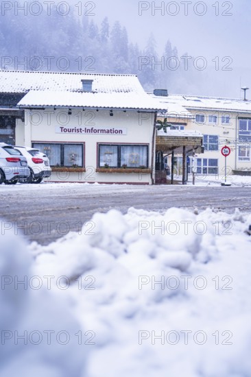 Tourist information centre with cars in the snow, situated under snow-covered roofs, Enzklösterle,