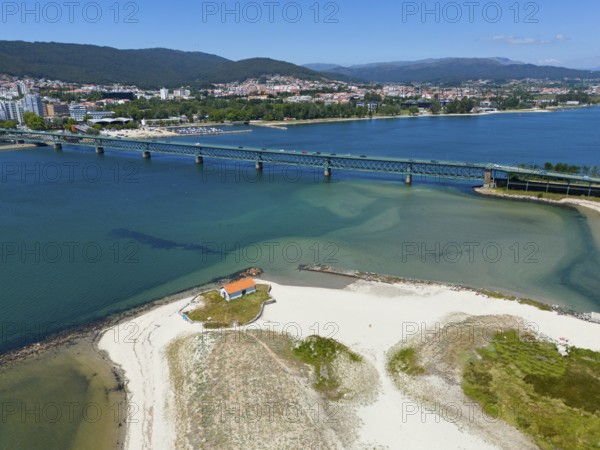 View of a city with hills connected by a bridge over a river that flows into the ocean, with a