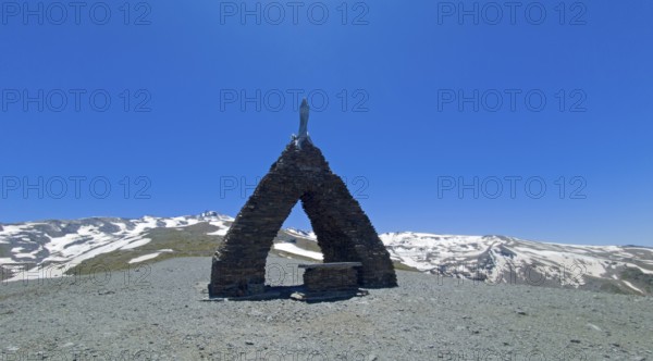 Chapel in a mountainous, snow-covered landscape under a clear blue sky, Virgen de las Nieves,