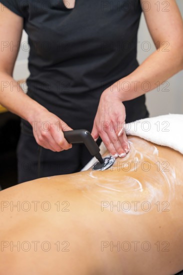 Vertical close-up photo of an unrecognizable massage therapist using the INDIBA machine to relieve