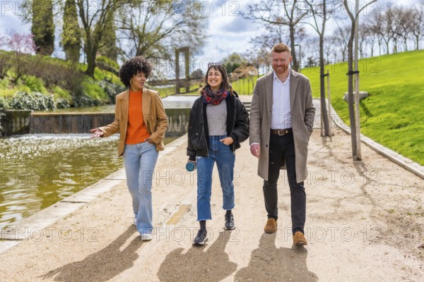 Three young professionals enjoy a walk and talk together during their lunch break in a sunny city