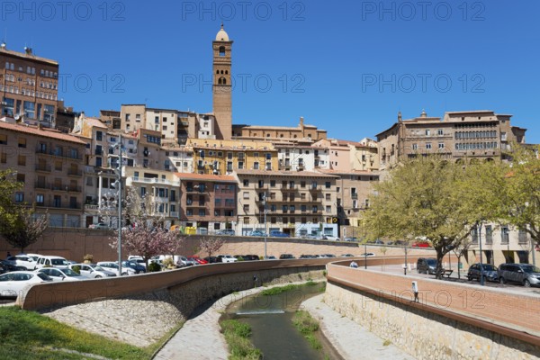 Cityscape with closely spaced houses and a river in the centre, dominated by a tower, church,