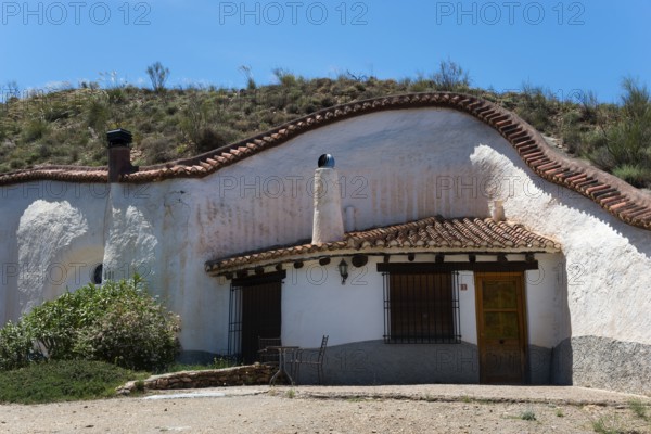 White house with charming rustic style in a hill with clear blue sky in summer, Cuevas del Zenete,