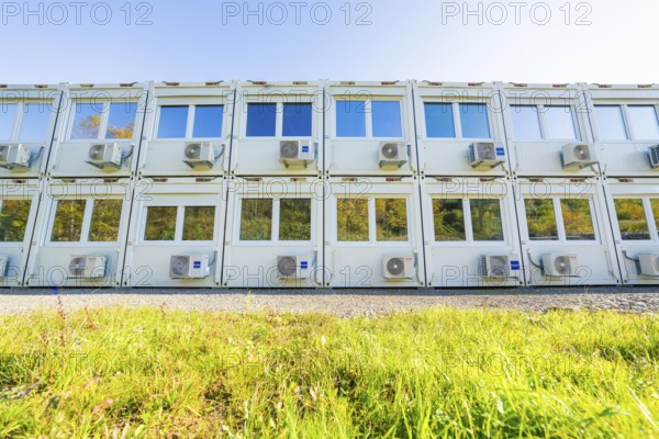 Several white containers with windows and air conditioning units stand on a green meadow, Beermiß