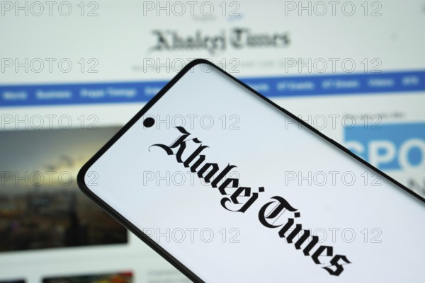 The logo of the newspaper khaleej times is displayed on a smartphone screen, and the website