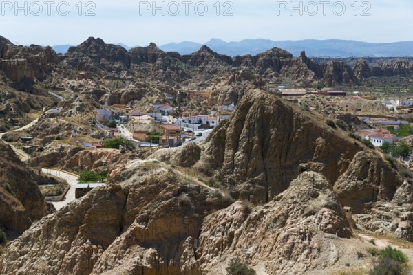 A small village nestled in a rocky, rugged landscape under a sunny sky, view from the Mirador del