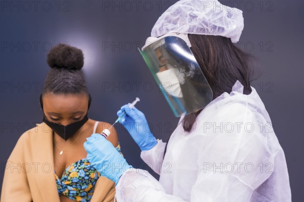 Black woman receiving the injection of the coronavirus vaccine by a doctor, antibodies, immunizes