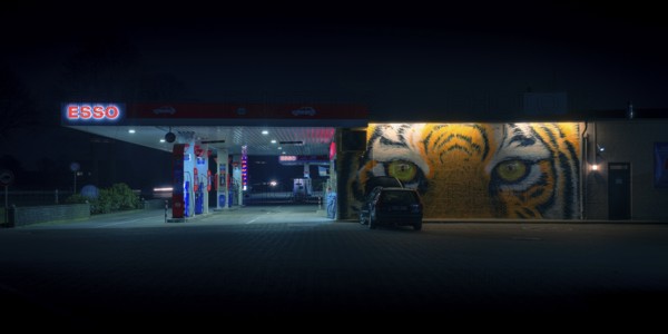 View of a petrol station with a parked car in front of a painted facade at night, Nienburg, Lower