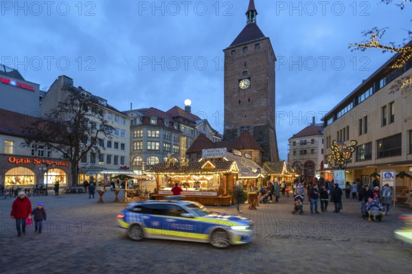 Christmas market, winter night at Jakobsplatz, behind White Tower, in front a passing police car,