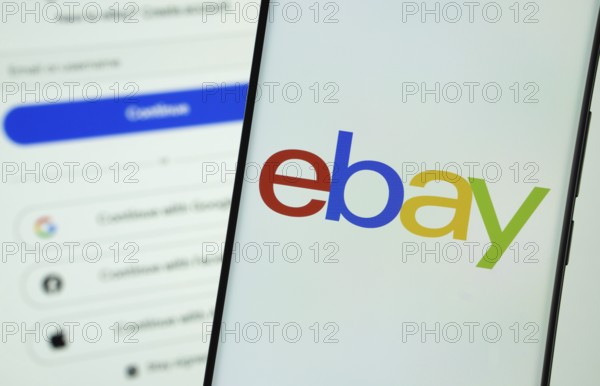 ebay logo is displayed on a smartphone screen, with the ebay login page visible on a computer