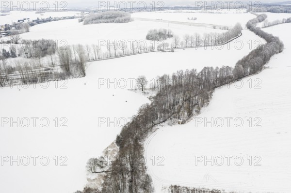 Aerial view of a winding tree-lined stream in the snow, between Eppendorf and Leubsdorf, Central