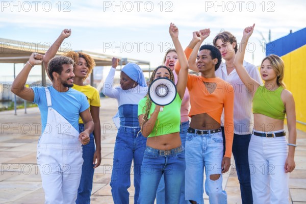 Multicultural and gender diverse young people yelling using a loudspeaker in a protest on an urban