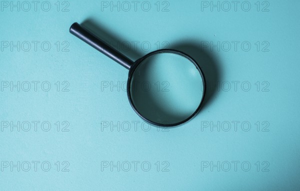 Magnifying Glass on Teal Background for Investigation Concept. CloseUp of Magnifying Glass for