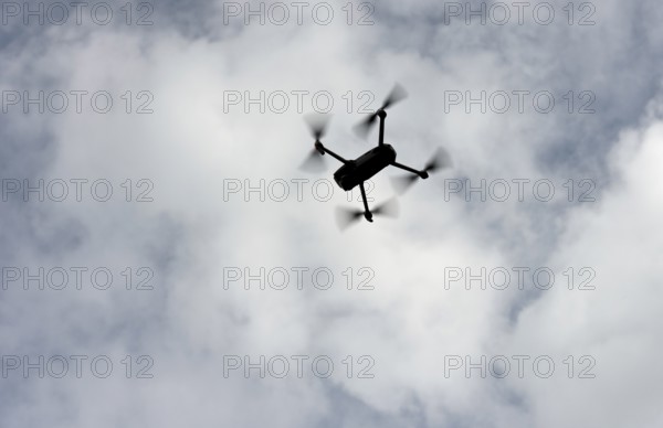 Silhouette of a drone in flight backlit against the sky, Switzerland