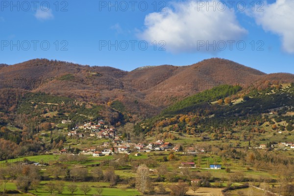 View of a village surrounded by autumnal hills and meadows, Erymanthos Mountains, northwest of the
