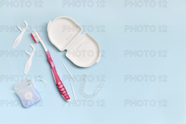 Top view of dental clear aligners, toothbrush, toothpicks and floss on blue background with copy