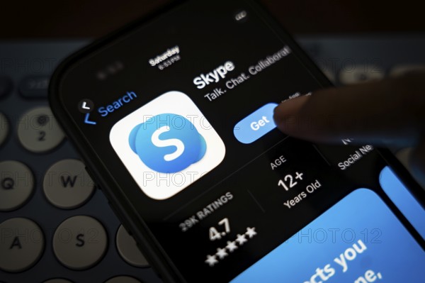 In this photo illustration, a person holds a mobile phone displaying Skype application, in