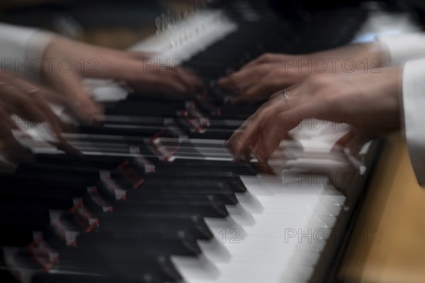 Moving hands of a young pianist playing on the keyboard of a Steinway & Sons grand piano,