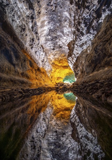 Lava tunnel, illuminated lava cave with perfect reflection in an underground lake, Cueva de los