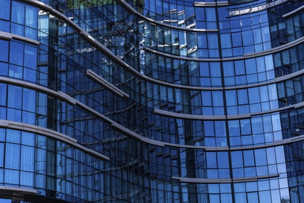 A close-up view of a modern building showcasing a curved glass facade with visible reflections and