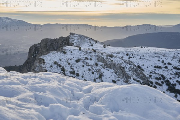 Scenic view of Montcabrer, Spain, showcasing its snow-covered peaks under a softly glowing sunrise.